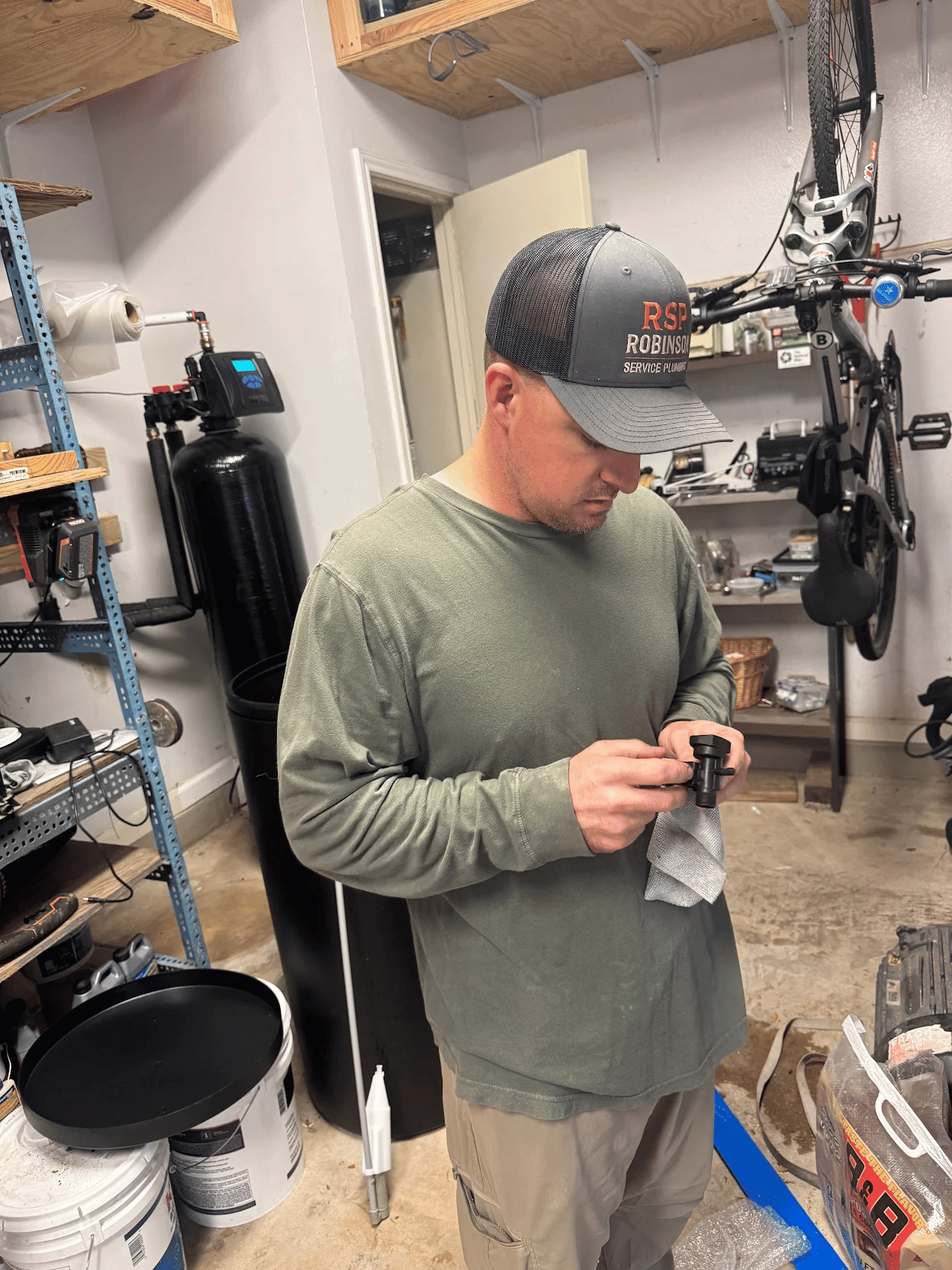 Robinson Service Plumbing technician inspecting a component while evaluating whether treatment equipment should be repaired or replaced