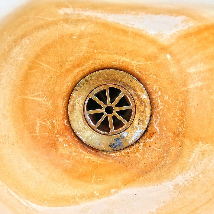 Orange iron staining around a household sink drain